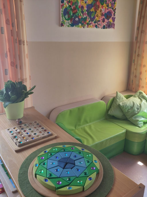 Gruppenraum mit grüner Sitzlandschaft und Spieltisch